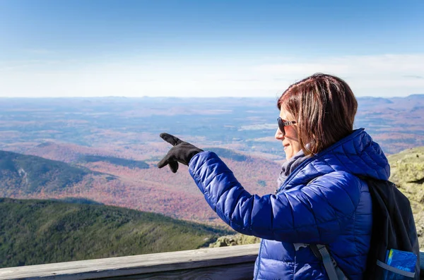 Женщина-турист на вершине горы, указывающая на красивые пейзажи — стоковое фото