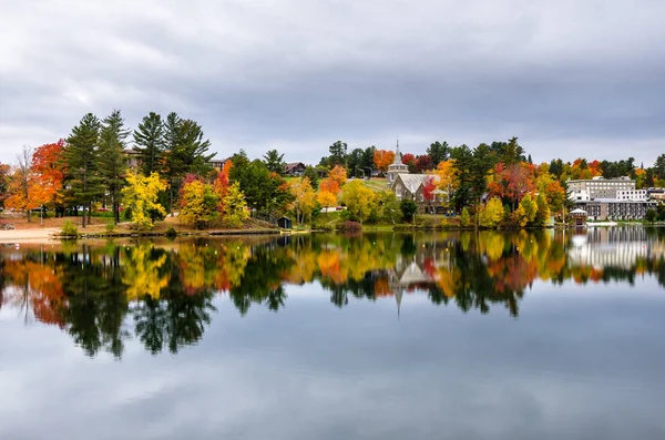 Edificios y coloridos árboles otoñales en la orilla de un lago y cielo nublado — Foto de Stock