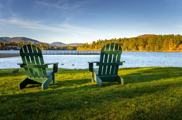Adirondack καρέκλες γκαζόν στην όχθη μιας λίμνης στο ηλιοβασίλεμα — Φωτογραφία Αρχείου
