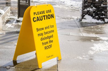 Sarı uyarı işareti düşen kar bir kaldırım üzerinde karşı