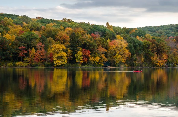 Canoa vermelha solitária em um belo lago de montanha no outono — Fotografia de Stock