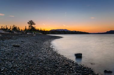 Alacakaranlıkta arka planda dağlar ile ıssız Beach