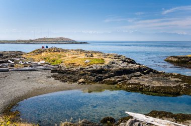 Sahil Park Ocean önünde iki renkli Adirondack sandalye ile. Bir deniz feneri bir ada ve bir dağ üzerinde arka planda görünür.