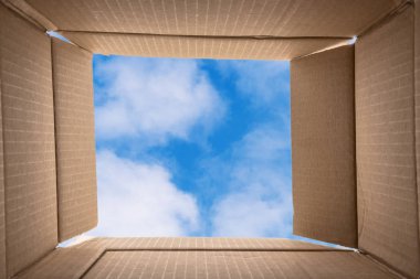 Kutunun dışında düşünme. Yaratıcı düşünme hakkında kavramsal görüntü: mavi gökyüzü arka plan ile açık bir karton kutu içine fotoğrafı. Kopya alanı