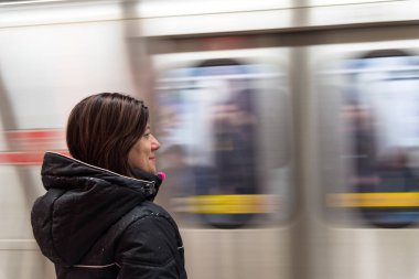  Kadın turist bir ıslak kış ceket bekleyen bir metro istasyonunda bir trenin. Toronto, Tarih, Kanada. Arka planda görünür bir gelen tren hareket olduğunu.