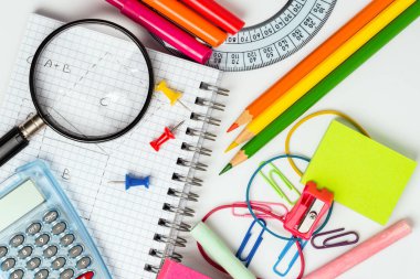 Renkli okul malzemeleri ve beyaz bir tablo açık bir defter. Eğitim kavramı