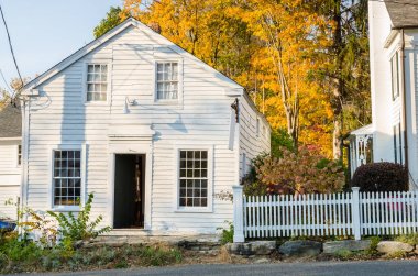 Güneşli bir sonbahar öğleden sonra arka planda renkli ağaçlar ile geleneksel New England ahşap ev. West Cornwall, Ct.