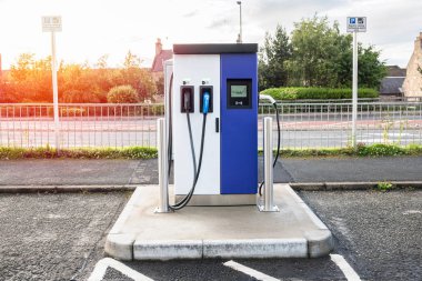 Gün batımında cadde boyunca bir otoparkta elektrikli araçlar için şarj noktası. Elgin, İskoçya, Uk.