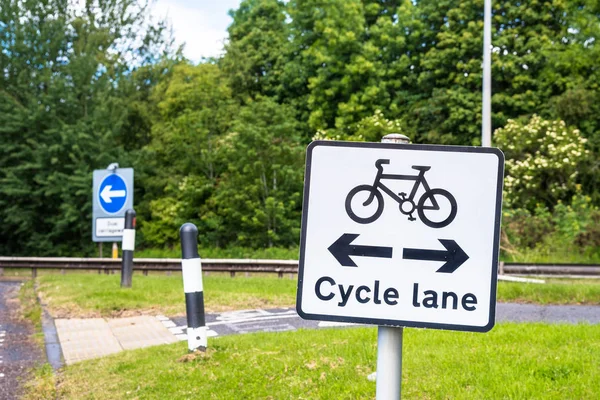 Sign on a road before the intersection with a bicycle lane. The cycle path is visible in background.