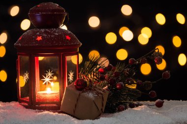 Arka planda bulanık ışıklar olan karla süslenmiş bir Noel fenerini kapat. Seçici odak ve kopyalama alanı.