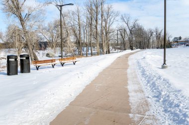 Bulutlu bir kış sabahı, karlı bir nehir kenarı parkında kardan temizlenmiş boş bir yol. Calgary, Ab, Kanada.
