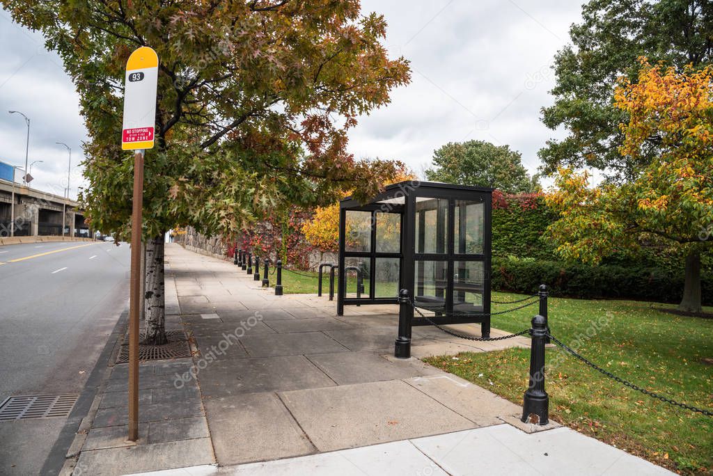 Empty bus shelter along a sidewalk on a cloudy autumn morning. Charlestown, MA, USA.