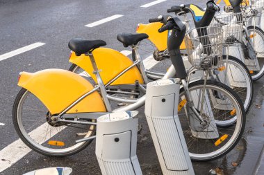 Yağmurlu bir günde ıslak bir cadde boyunca bir rıhtımda bisiklet paylaşmak. Brüksel, Belçika.