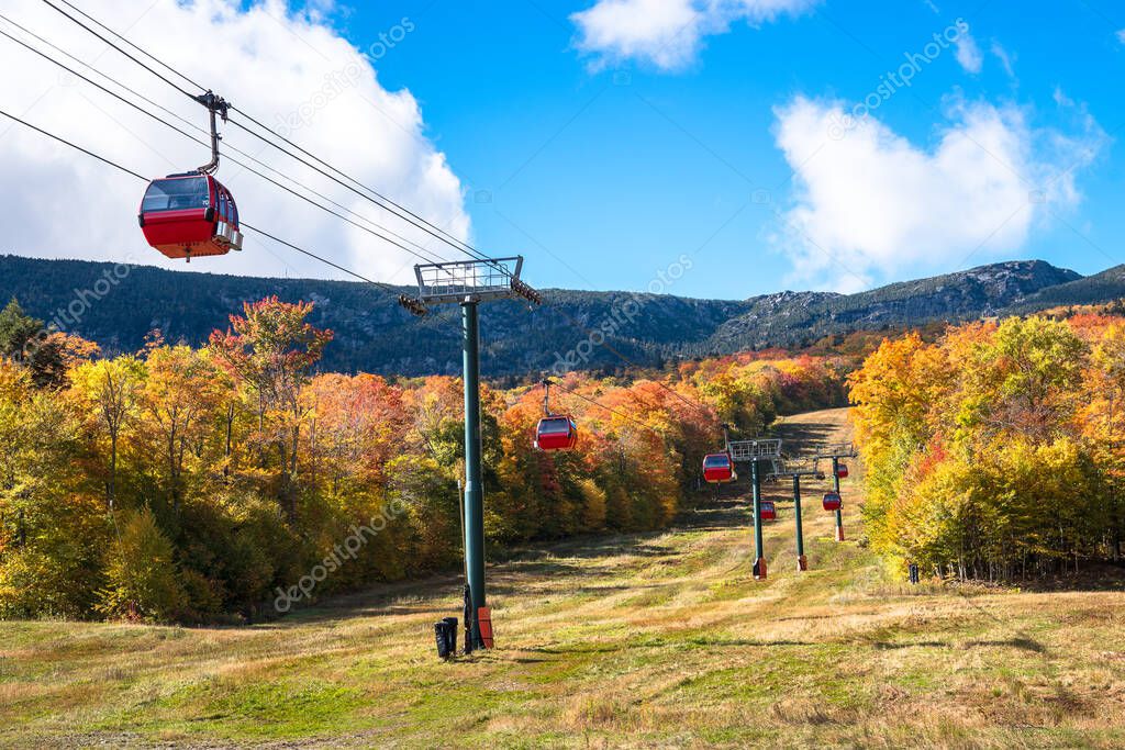 Overhead cable car over a wooded slope to a mountain peak on a sunny autumn day. Beautiful fall foliage. Stowe, VT, USA.