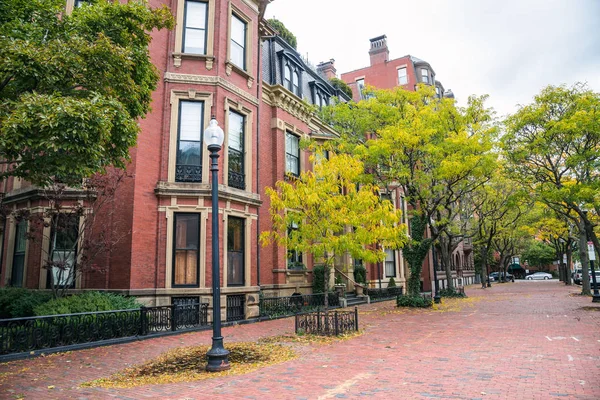 Bulutlu bir sonbahar gününde ağaç kaplı tuğla kaldırım boyunca geleneksel konut binaları. Boston, MA, ABD.