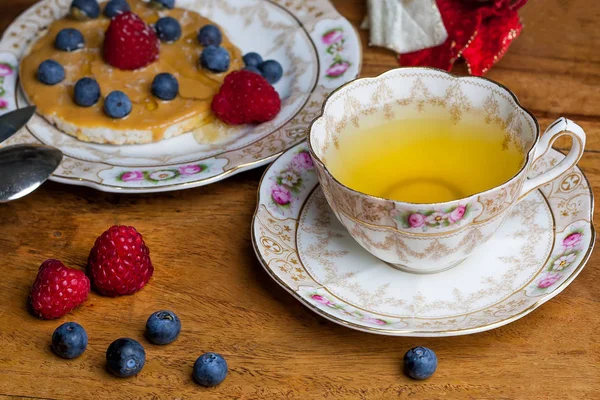 Fincan çay, sauser, pirinç kraker fıstık ezmesi, çilek ve