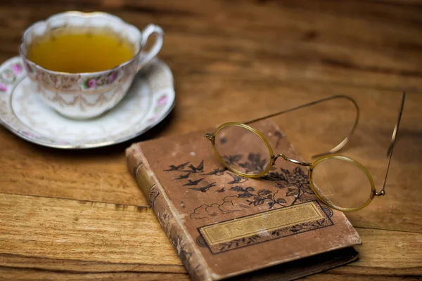 Livro velho na mesa de madeira, óculos vintage, xícara de porcelana o — Fotografia de Stock