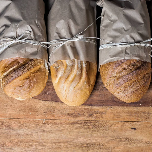 different bread on the wooden table, flour, paper bags, rope