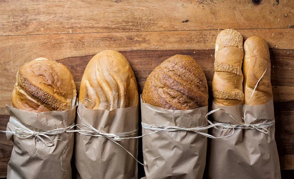 different bread on the wooden table, flour, paper bags, rope