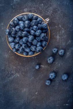 Koyu arkaplanda cam bir kasede taze yabanmersini.