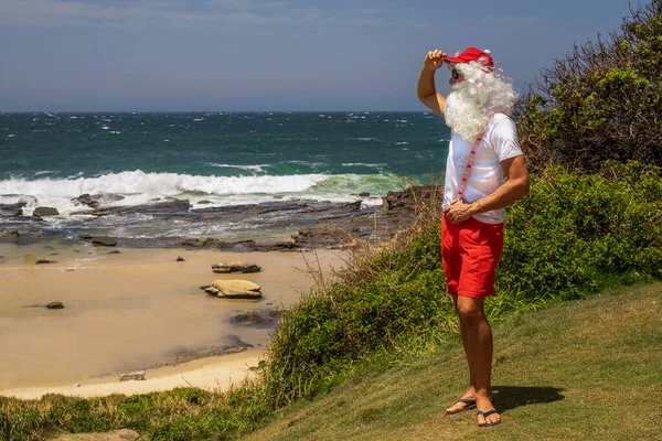 Santa Claus holds gift boxes with the ocean on backgraund — Stock Photo, Image