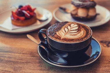 Bir fincan kahve, masanın üstünde sanat, arka planda bulanık çöller.