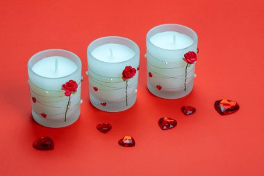 Aroma candles decorated with roses and hearts on red background