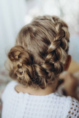 Festive hairstyle from braid on a child girl with long hair, back view