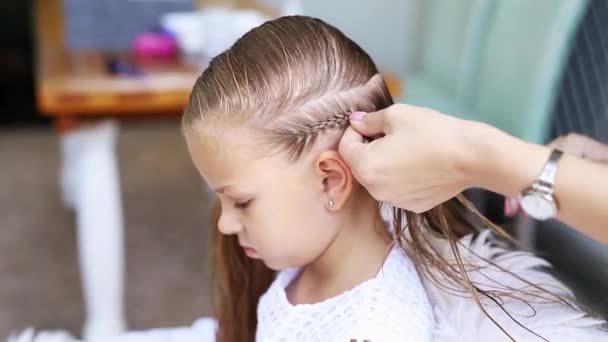 Mother braids her daughters long blond hair. Caucasian womans hands. Small  girl in white dress sitting in chair and watching down. — Stock Video ©  @ #346677452