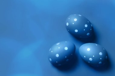 Mavi arka planda renkli yumurtalar. Paskalya konsepti, bedava kopya alanı olan kart