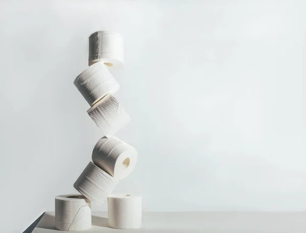 Rollos de papel higiénico inestable de pie uno sobre el otro sobre fondo blanco — Foto de Stock