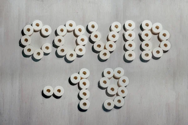 Titolo Covid-19 realizzato con rotoli di carta igienica su sfondo bianco in legno . Foto Stock