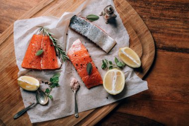 Limonlu taze çiğ somon, tahtanın üzerinde bitkiler ve baharatlar.