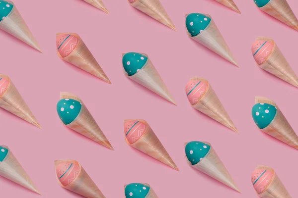 Modèle avec des œufs colorés décorés dans des cônes de bambou ressemblent à de la crème glacée sur fond rose . — Photo