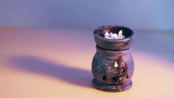 Flacone di vetro verde Dropper. gocce oleose cadono dalla pipetta cosmetica in acqua con fiori in lampada a candela . — Video Stock