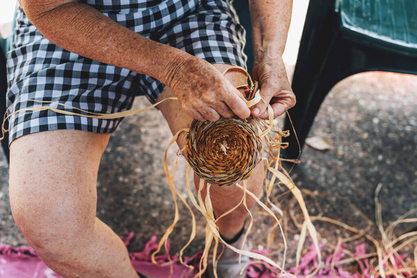 Old female weaving basket on the craft workshop. Hands holding the craftwork, close up shot