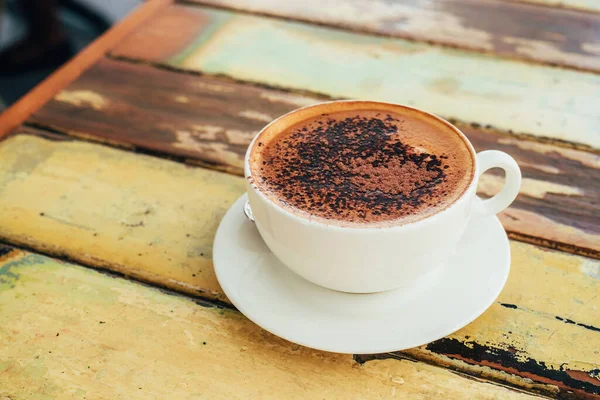 Weiße Tasse Cappuccino mit Schokoladenpuder auf dem rustikalen Holztisch — Stockfoto