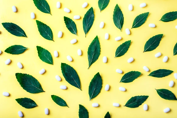 Modèle de feuilles de menthe et de pilules blanches pour une respiration rafraîchissante sur fond jaune . — Photo