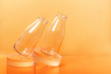 Cam şişeler süt ambalajları turuncu arka planda duruyor..