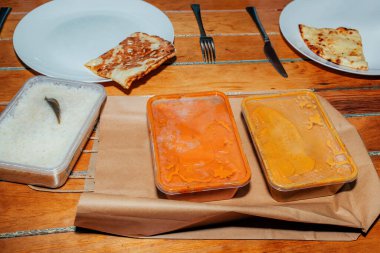 Hint restoranından yemek geldi. Götürün. Masada lezzetli yemekler ve tabakta ekmek olan plastik kaplar.