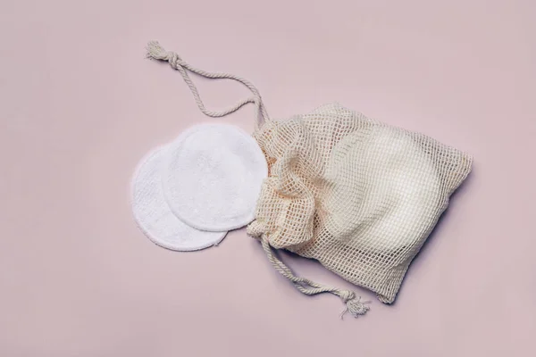 Reusable Bamboo Cotton Makeup Remover Pads in net bag on pink background. Zero-waste, sustainable lifestyle concept