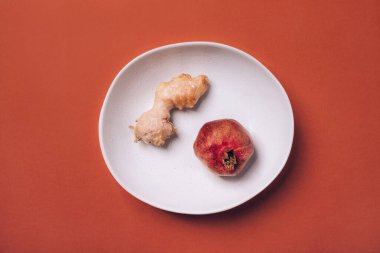 Turuncu arka planda olgun nar ve zencefil kökü.