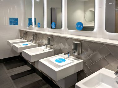 İnsanların koronavirüs hastalığından korunmak için umumi tuvaletteki lavabo ve aynaların üzerine yapıştırmalar yapıştırıp sosyal mesafeyi takip etmeleri için.