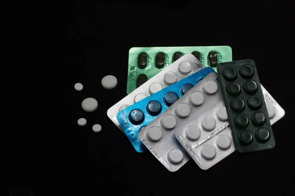 Sininen vihreä valkoinen pillereitä mustalla taustalla — kuvapankkivalokuva