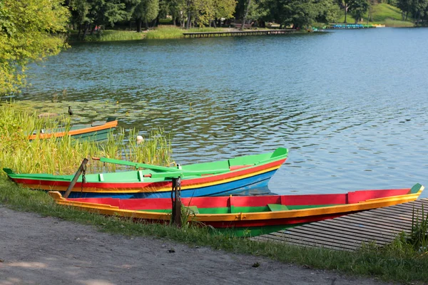 Barcos coloridos perto da costa do lago e um pontão no fundo da água e da floresta — Fotografia de Stock