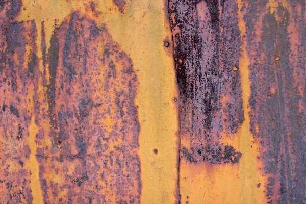 The flaking yellow color with scratched on the surface of rusty galvanized iron plate. Rusty yellow painted metal wall. Rusty metal background with strips of rust. Rust spots. Metal surface rust stains
