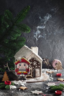close-up photo of Christmas ginger house with toy, red candles and green fir tree on concreted table and wall background  clipart