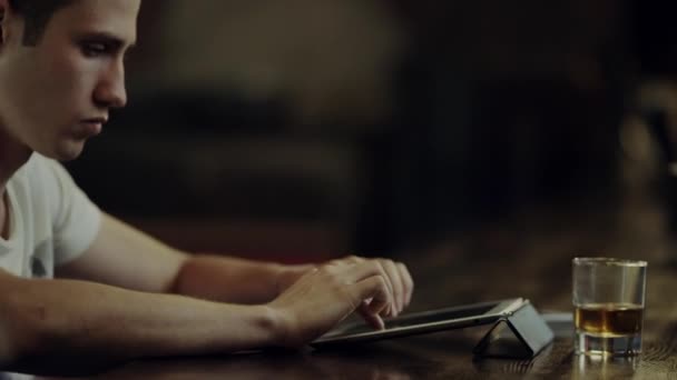 Hombre escribiendo en una tableta en un mostrador de bar — Vídeo de stock