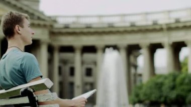 adam bir bankta dizüstü bilgisayar ile