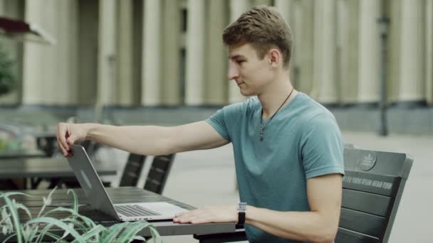 Kerl öffnet den Laptop und beginnt ihn n Café zu benutzen — Stockvideo